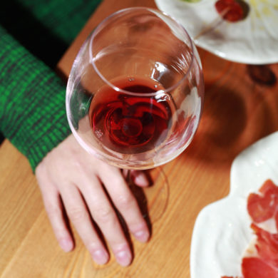 Hand holding a wine glass with red wine during a Portuñol Wine Tasting event